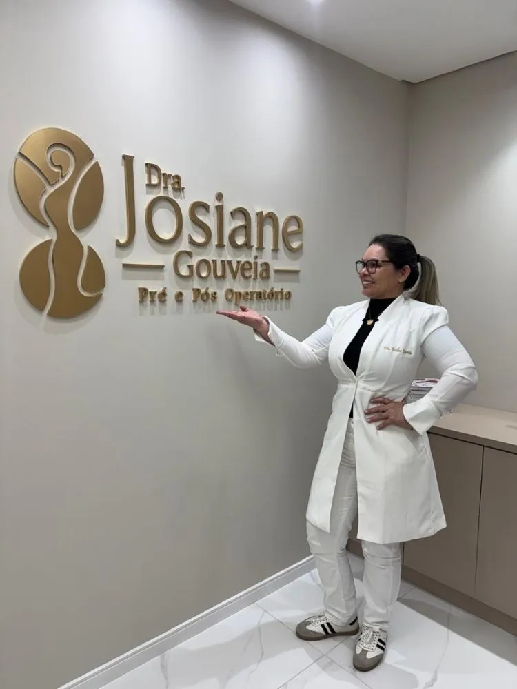 Dra. Josiane Gouveia ao lado da logo da clínica